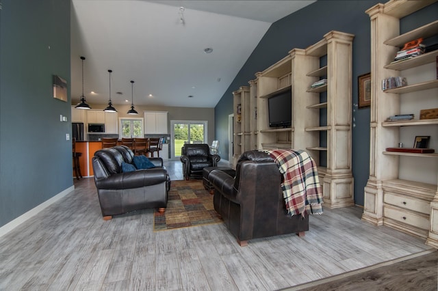 living room featuring high vaulted ceiling, built in features, and light hardwood / wood-style flooring