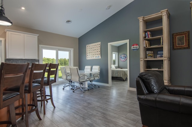 dining area with wood-type flooring and vaulted ceiling