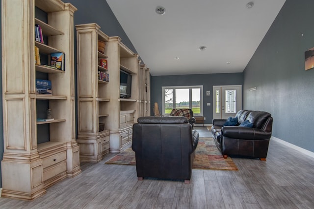 living room with hardwood / wood-style flooring, built in features, and vaulted ceiling