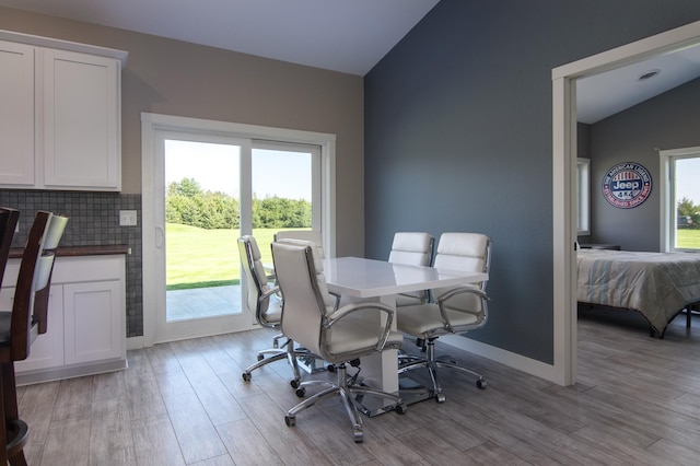 dining space featuring vaulted ceiling, light wood-style flooring, and baseboards