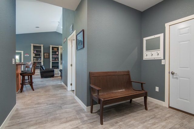 living area with lofted ceiling, light wood-style flooring, and baseboards