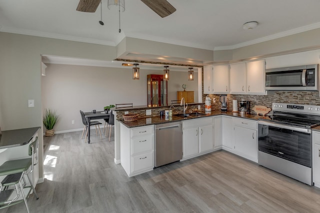 kitchen with stainless steel appliances, sink, white cabinetry, decorative backsplash, and dark stone counters