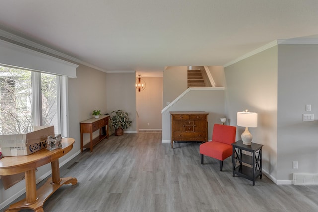 sitting room with ornamental molding, light hardwood / wood-style flooring, and an inviting chandelier