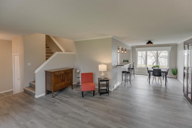 sitting room with light wood-type flooring and crown molding