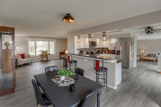 dining space featuring ornamental molding, ceiling fan, and light hardwood / wood-style flooring