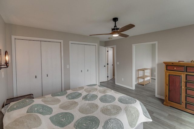 bedroom featuring multiple closets, ceiling fan, and light hardwood / wood-style floors