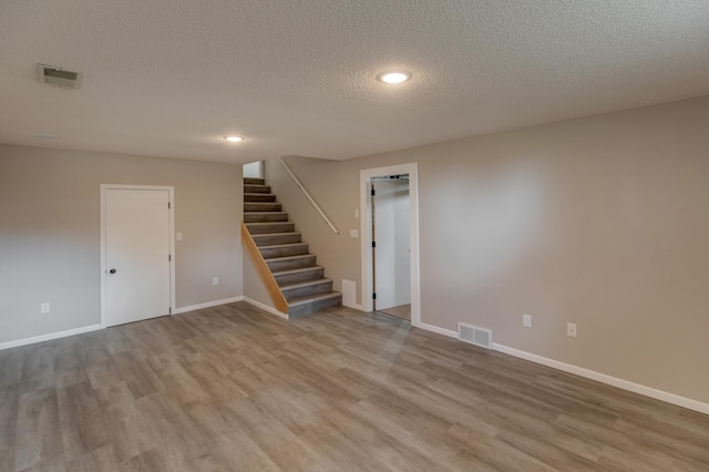 spare room featuring a textured ceiling and light hardwood / wood-style flooring