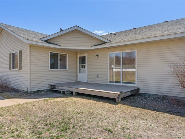 back of property featuring a deck and a lawn