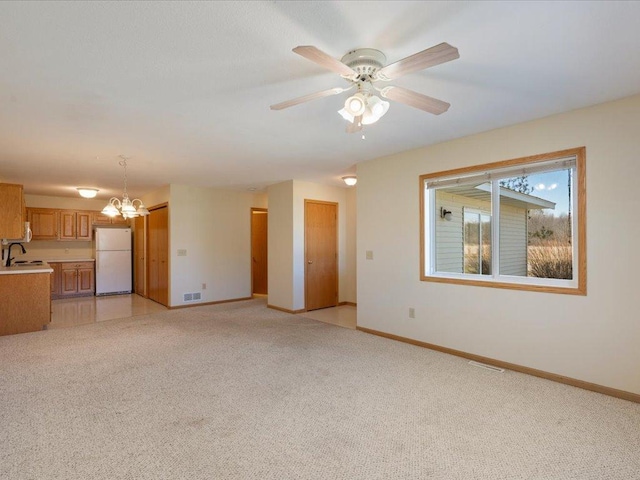 interior space with light colored carpet, sink, and ceiling fan with notable chandelier