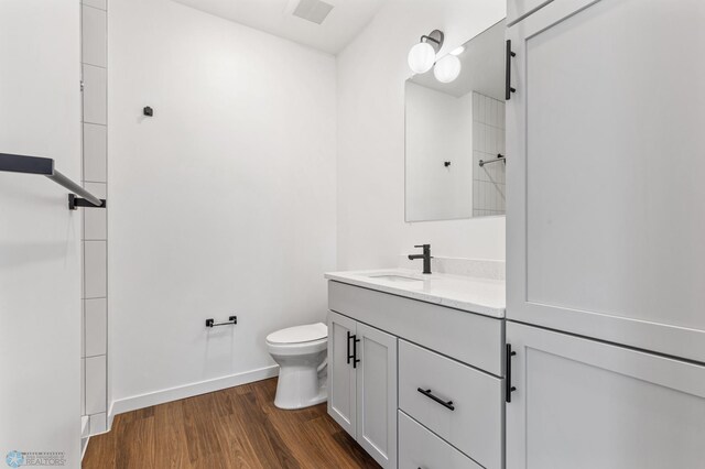 bathroom with wood-type flooring, vanity, and toilet