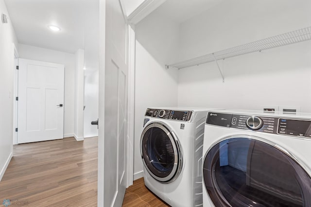 clothes washing area with wood-type flooring and washer and clothes dryer