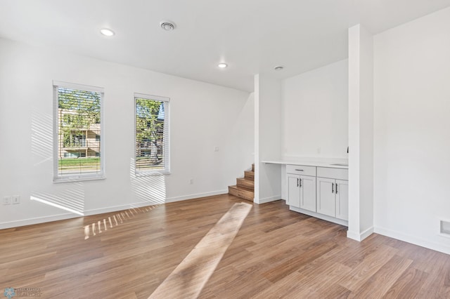 spare room with stairs, recessed lighting, baseboards, and light wood-type flooring