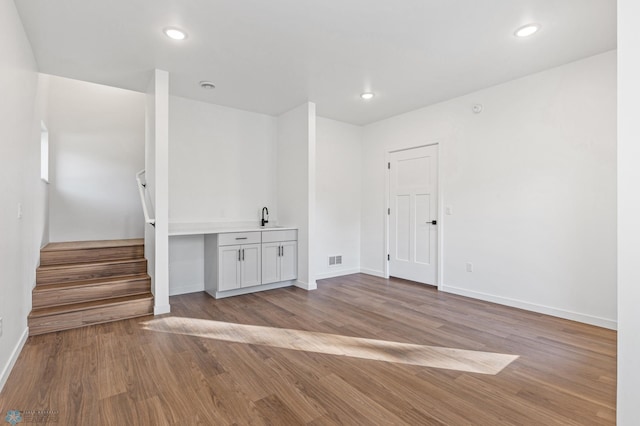 interior space with baseboards, stairs, wood finished floors, and visible vents