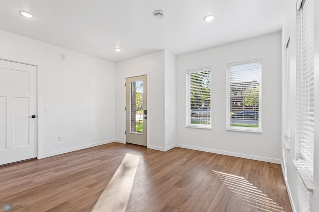 spare room featuring baseboards, recessed lighting, wood finished floors, and visible vents