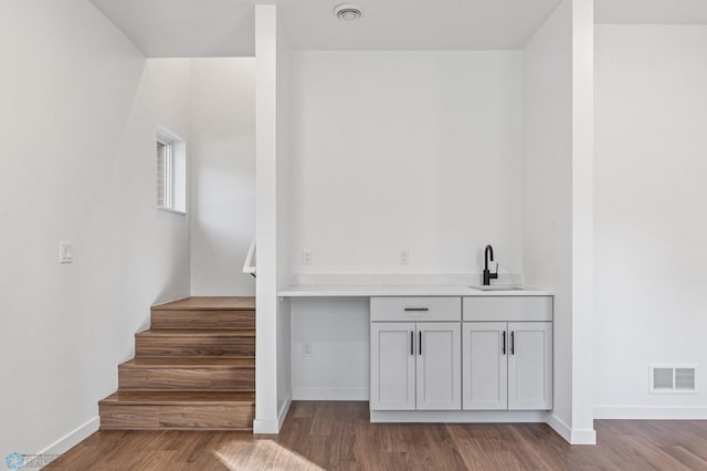 bar featuring visible vents, a sink, baseboards, and wood finished floors