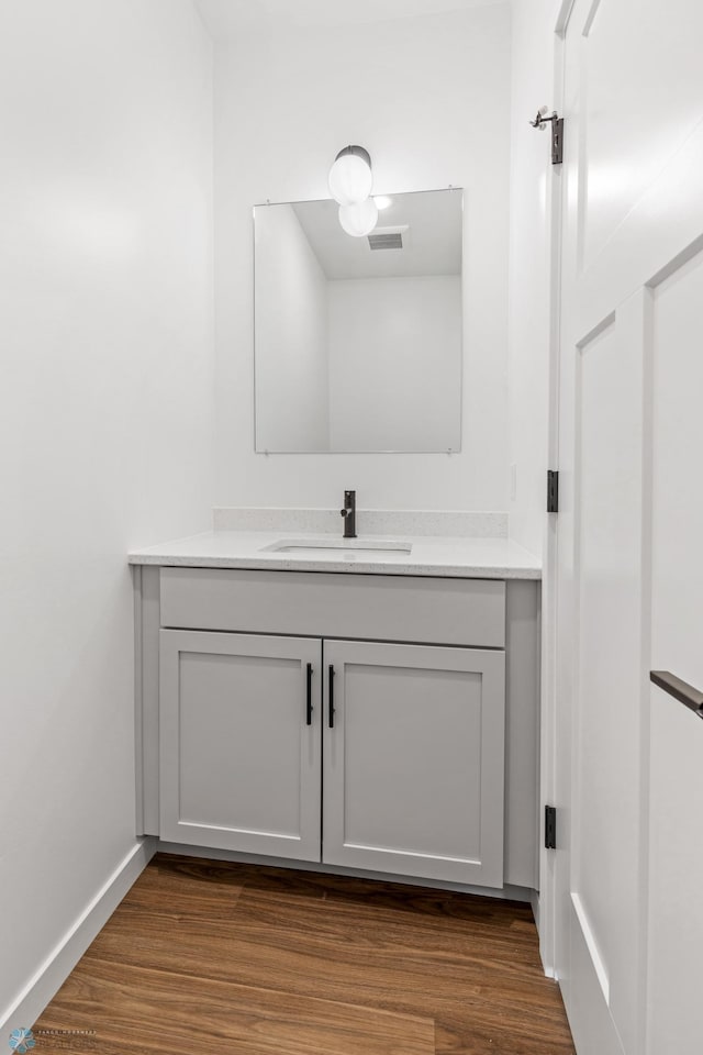 bathroom with vanity, baseboards, wood finished floors, and visible vents