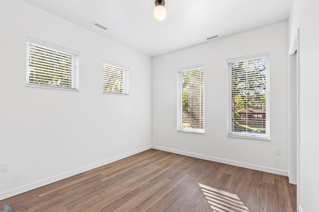 spare room featuring baseboards, wood finished floors, and visible vents