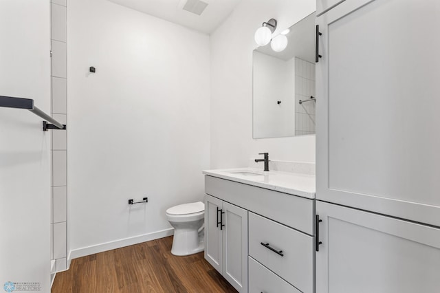 bathroom featuring vanity, toilet, baseboards, wood finished floors, and visible vents