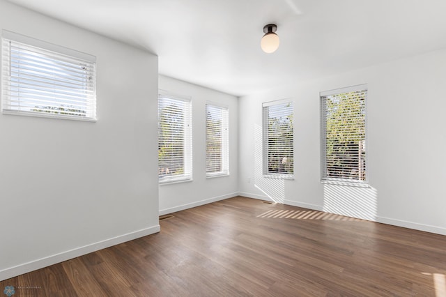 spare room featuring baseboards and wood finished floors