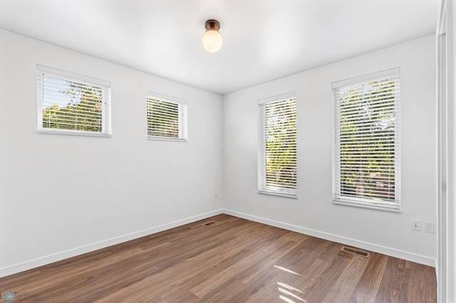 unfurnished room with baseboards, dark wood-type flooring, and visible vents
