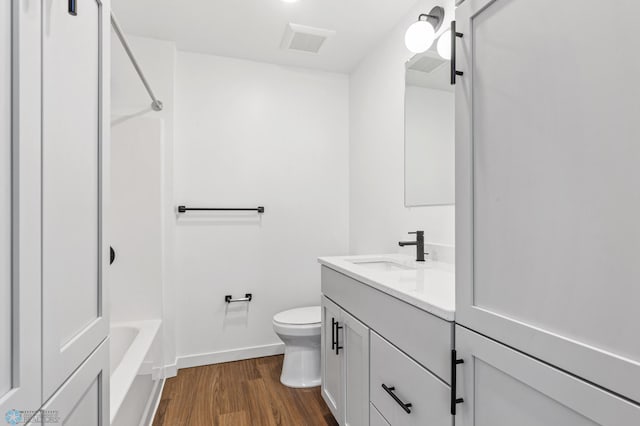 bathroom featuring vanity, visible vents, wood finished floors, toilet, and shower / tub combination