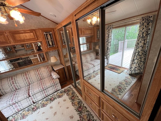 interior space with wooden walls, ceiling fan with notable chandelier, hardwood / wood-style floors, and lofted ceiling