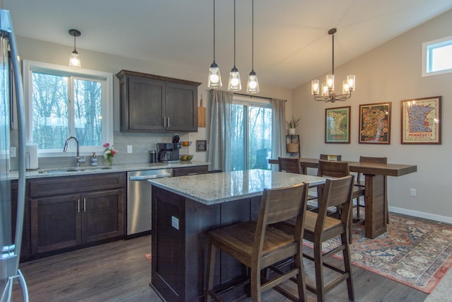 kitchen with an inviting chandelier, a kitchen bar, dark wood-type flooring, a sink, and stainless steel appliances
