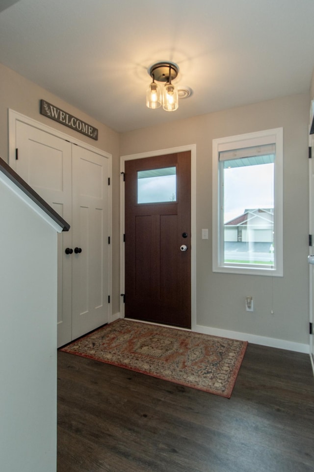 foyer with dark wood-style flooring and baseboards
