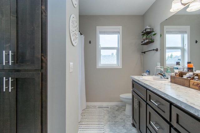 bathroom featuring visible vents, a healthy amount of sunlight, toilet, and vanity