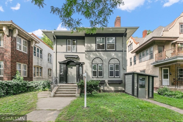 view of front of house with a balcony and a front lawn