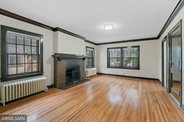 unfurnished living room featuring light hardwood / wood-style flooring, radiator, a brick fireplace, and ornamental molding