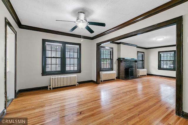 unfurnished living room with light wood-type flooring, radiator heating unit, and plenty of natural light