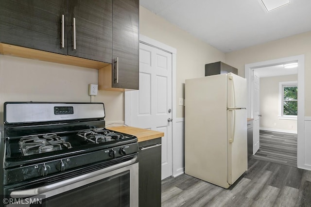 kitchen with dark brown cabinets, stainless steel gas stove, dark wood-type flooring, and white fridge