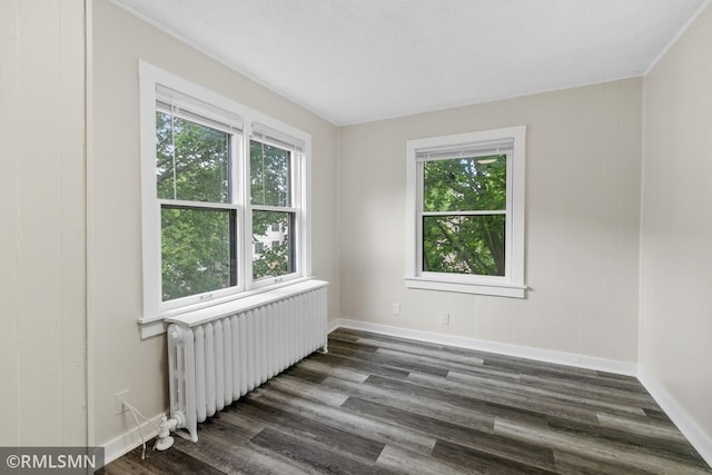 spare room featuring ornamental molding, plenty of natural light, dark hardwood / wood-style flooring, and radiator heating unit