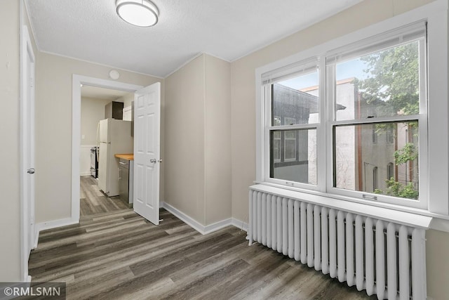 hallway with a textured ceiling, dark hardwood / wood-style floors, and radiator heating unit