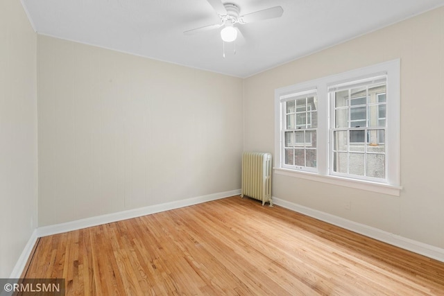 spare room with radiator, hardwood / wood-style floors, and ceiling fan