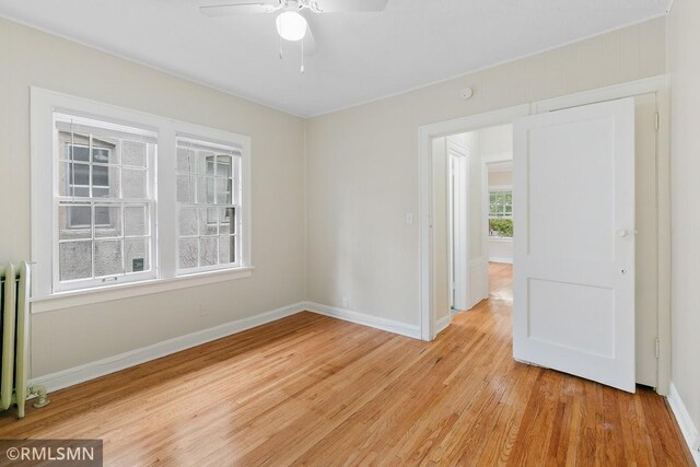 unfurnished room featuring radiator, ceiling fan, and light hardwood / wood-style flooring