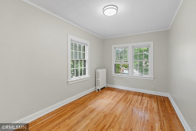 empty room featuring ornamental molding, radiator, light hardwood / wood-style floors, and a textured ceiling