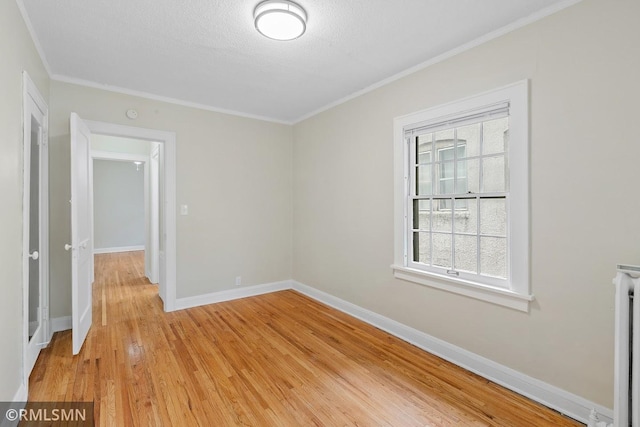 spare room with a textured ceiling, crown molding, and light hardwood / wood-style floors