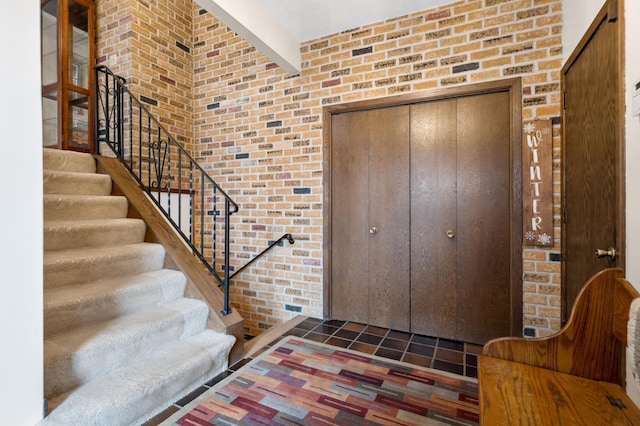 foyer entrance featuring dark tile patterned flooring and brick wall