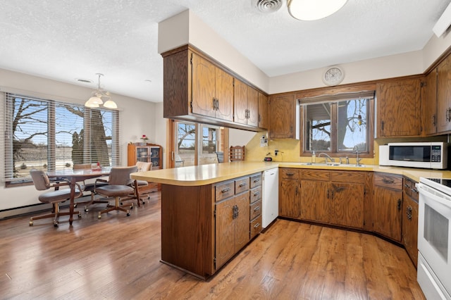 kitchen featuring sink, white appliances, decorative light fixtures, kitchen peninsula, and light wood-type flooring