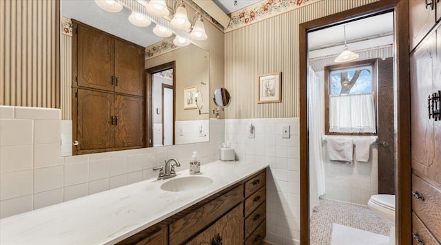 bathroom with tile walls, vanity, and toilet