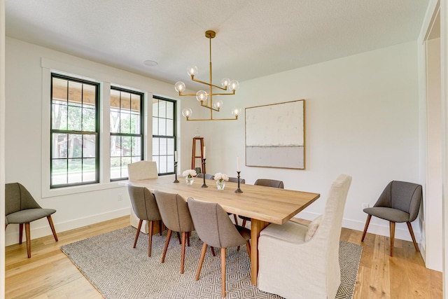 dining space featuring a chandelier, a textured ceiling, and light wood-type flooring