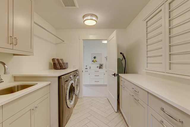 laundry room with cabinets, sink, washer and dryer, a textured ceiling, and light parquet flooring