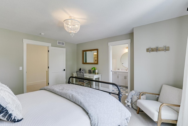 carpeted bedroom with a textured ceiling, ensuite bathroom, and a notable chandelier