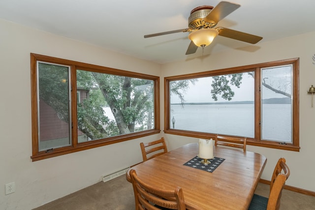 carpeted dining area with a water view and ceiling fan