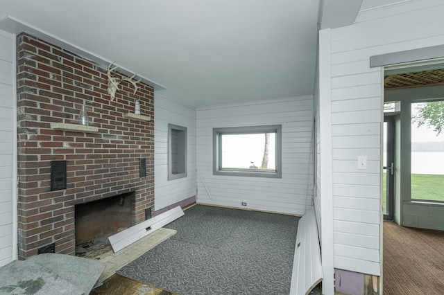 unfurnished living room with brick wall, a fireplace, and a wealth of natural light