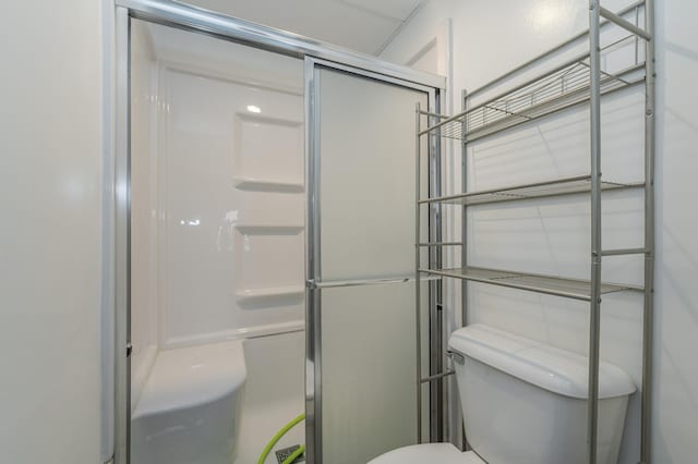 bathroom with a shower with shower door and toilet