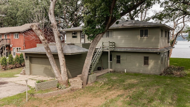 back of property featuring driveway, a lawn, and roof with shingles