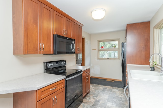 kitchen with a sink, black appliances, and light countertops